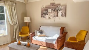 A living room with a sofa, two yellow armchairs, a coffee table, and a wall art piece. - 4-Bedroom Villa • Secure Pool • Air Conditioning • Provence – Bollène (Bollène)
