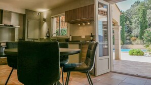 A modern kitchen with a dining area, large windows, and a view of a swimming pool. - 4-Bedroom Villa • Secure Pool • Air Conditioning • Provence – Bollène (Bollène)