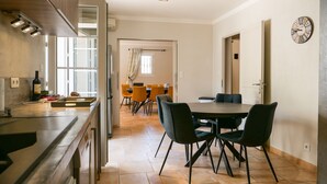 A modern kitchen with a dining area, featuring a large table and chairs, a clock on the wall, and a window providing natural light. - 4-Bedroom Villa • Secure Pool • Air Conditioning • Provence – Bollène (Bollène)