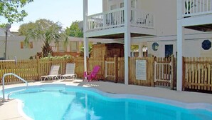 Piscina com espreguiçadeiras e cerca de madeira.