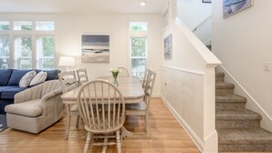 A dining area with a wooden table and chairs, a sofa, and a staircase. - Private Pool ~ Porch ~ Fire Pit ~ Pet Friendly (Destin)