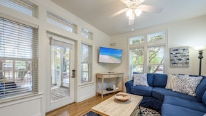 A living room with a blue sectional sofa, a wooden coffee table, and a flat-screen TV on the wall. - Private Pool ~ Porch ~ Fire Pit ~ Pet Friendly (Destin)