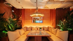A cozy seating area with a wooden table and cushioned sofas, surrounded by plants. - Second Nature London Chiswick (London)