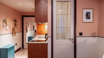 A hotel room with a wooden vanity, a bed, a door with a window, and a framed picture on the wall.