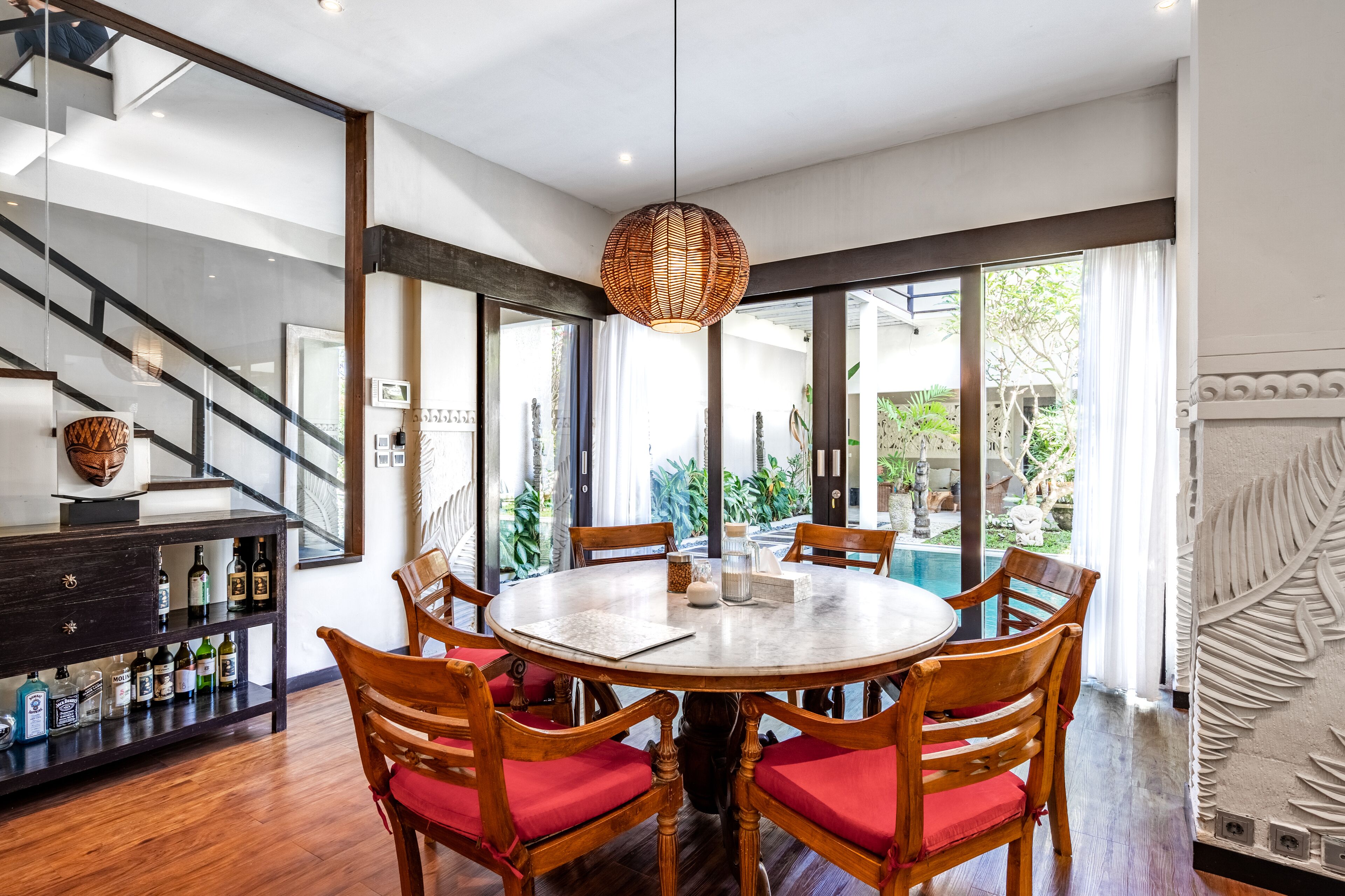 A dining area with a round table, wooden chairs, and a hanging light fixture.