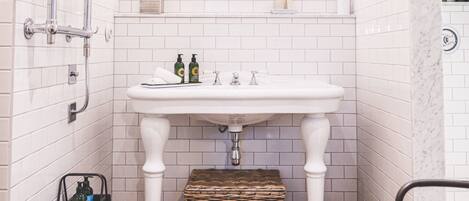 Un baño con un lavabo blanco, espejo y paredes con azulejos.