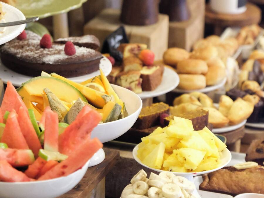 Un bufet amb diversos plats, incloent fruita, pastissos i postres.