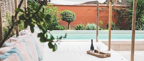 Una piscina al aire libre, sombrillas, sillones reclinables de piscina