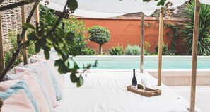 Una piscina al aire libre, sombrillas, sillones reclinables de piscina