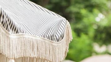 A close-up of a striped fabric with fringe details, likely part of a piece of outdoor furniture.