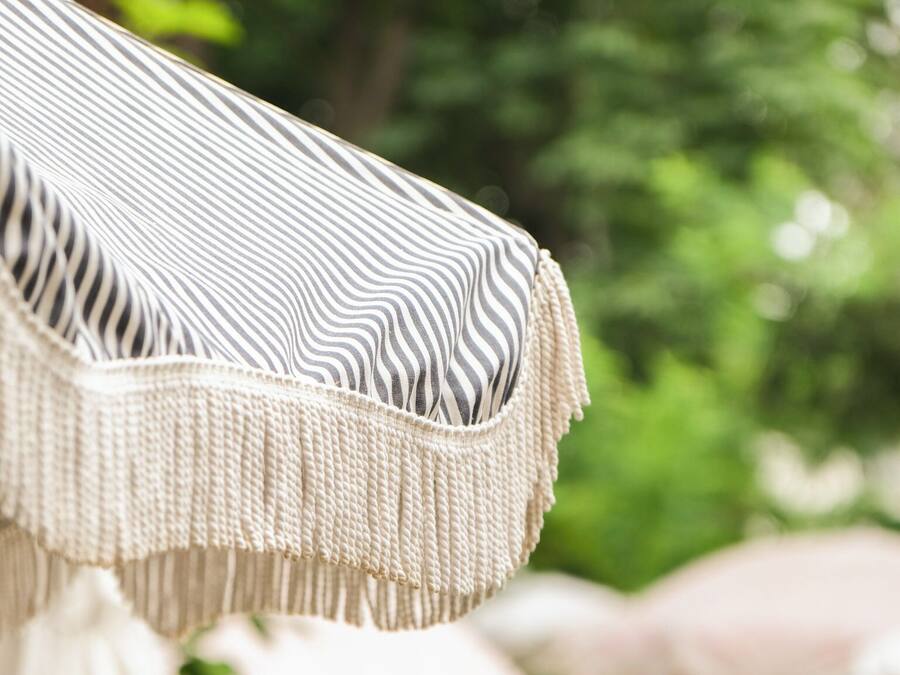 A close-up of a striped fabric with fringe details, likely part of a piece of outdoor furniture.