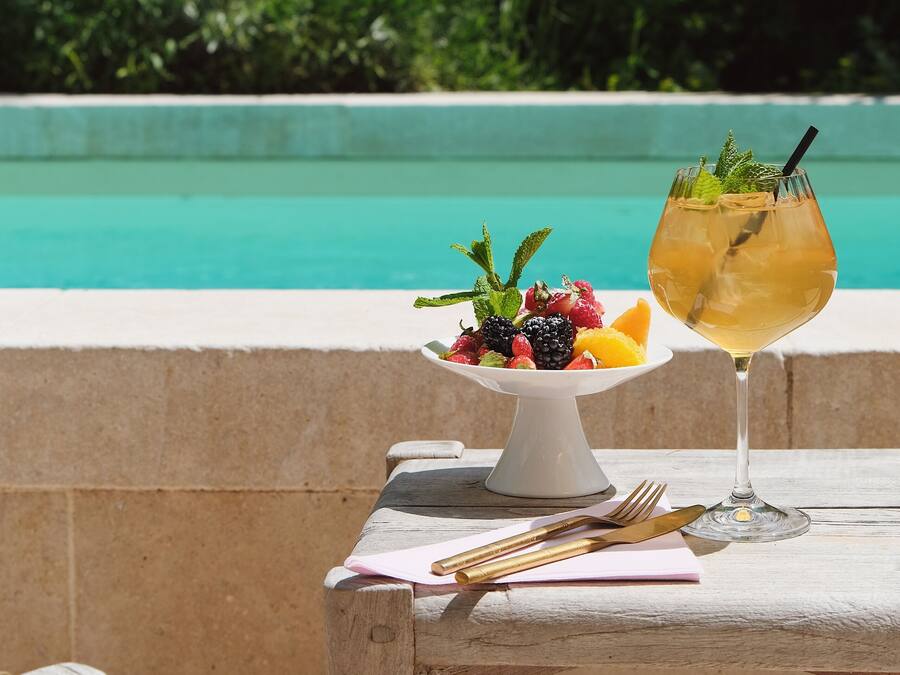 Ein Tisch mit Obstplatte und Cocktailglas am Pool.