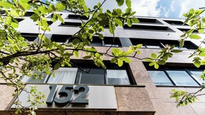 A building with the number 152 on its facade, surrounded by greenery.