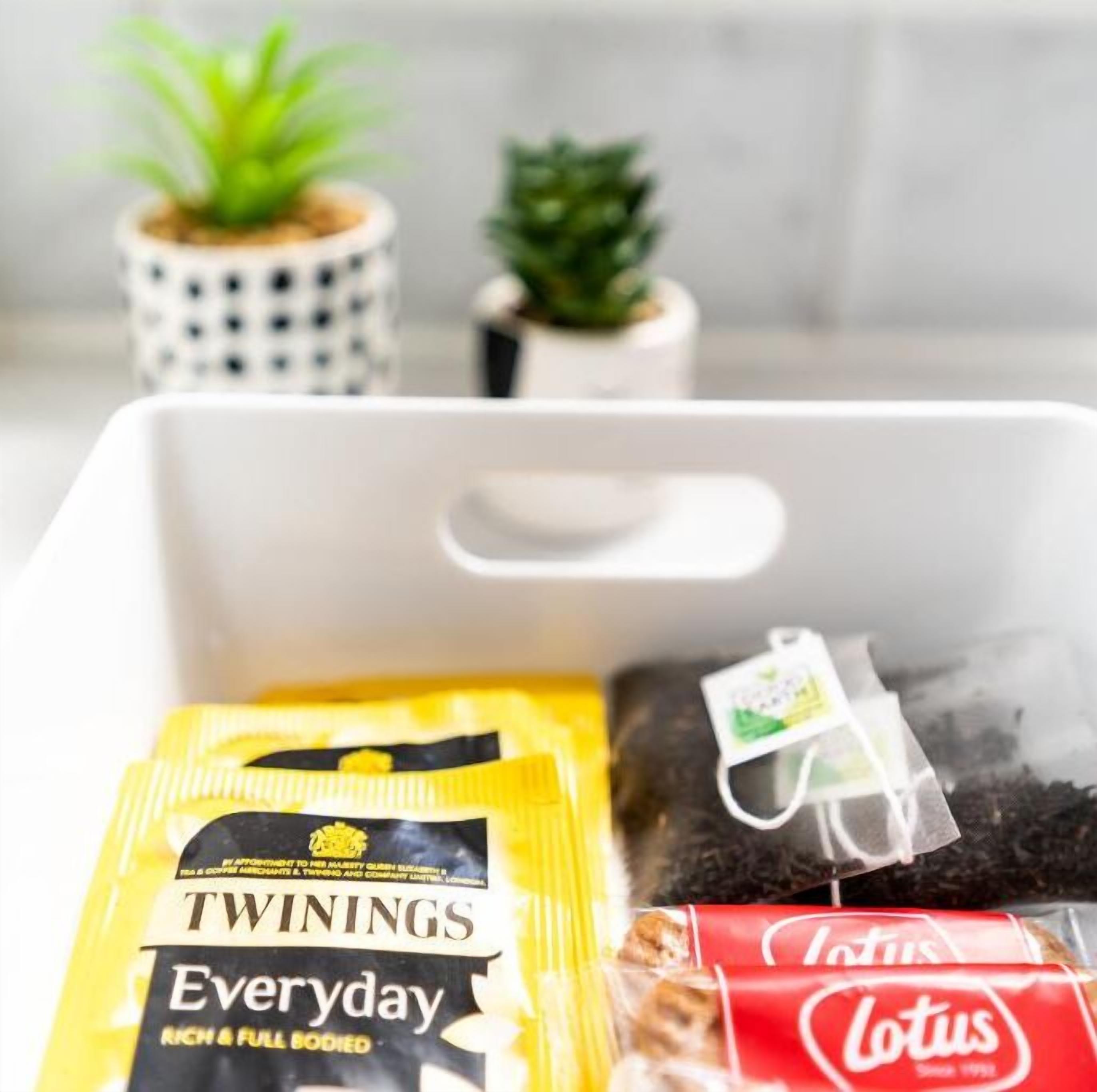 Een witte opbergdoos met Twinings Everyday thee, een pak Lotus sigaretten en een theezakje.
