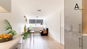 A modern kitchen with a dining area, a sofa, and a potted plant.