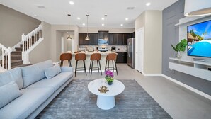 A modern living room with a sofa, coffee table, and TV. - Elegant Townhome, Private Splash Pool, Near Theme Parks! (Davenport)