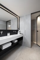 Un baño moderno con un espejo grande, dos lavamanos y un perchero para toallas.