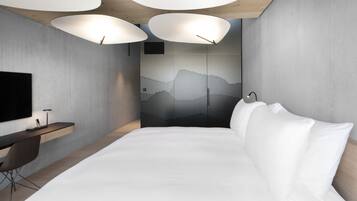 Une chambre d’hôtel moderne, dotée d’un grand lit, d’un bureau et d’un téléviseur fixé au mur.