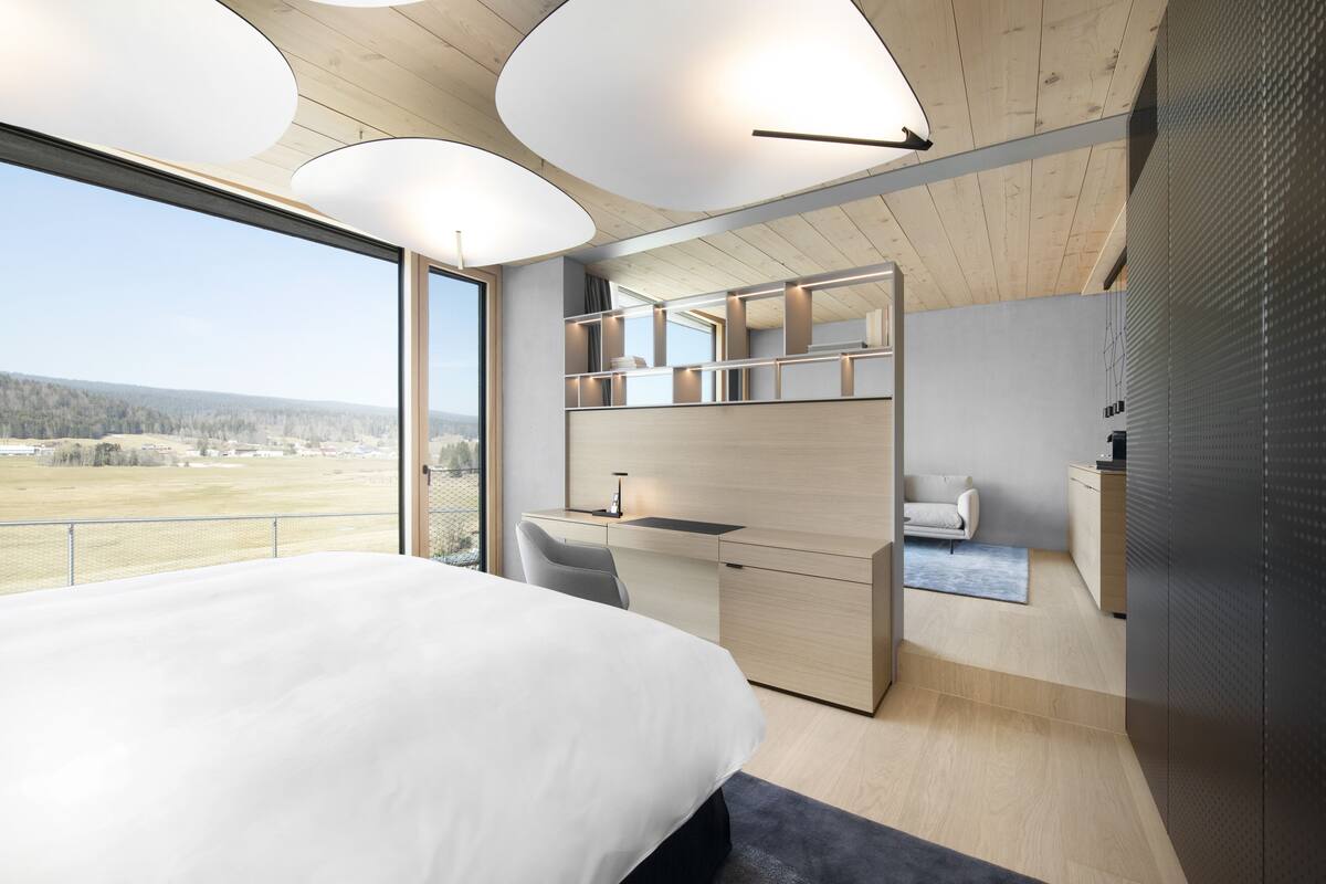A modern bedroom with a large bed, a desk, and a built-in wardrobe.