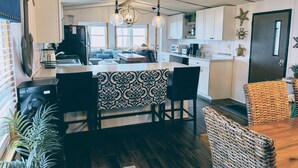 A modern kitchen with a dining area, wooden flooring, and a central island.