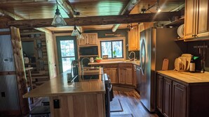 A modern kitchen with wooden cabinets, a stainless steel refrigerator, and a large island.