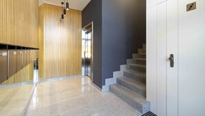A modern interior with a staircase, lockers, and a wall-mounted elevator.