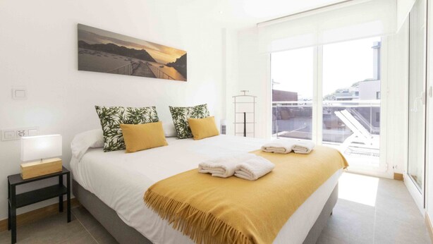 A modern hotel room with a large bed, a nightstand, a lamp, and a painting on the wall.