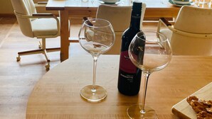 Una mesa de comedor dispuesta con copas de vino y una botella, con vistas a un paisaje marino.