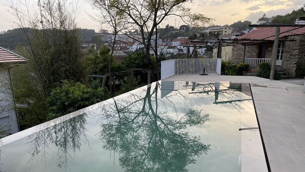 A swimming pool with a clear view of the surrounding area, including trees and buildings. - Stunning Villa. Discover some details from several generations (Sever do Vouga)