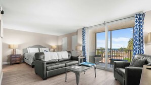 A modern hotel room with a bed, two sofas, a coffee table, and a balcony with a view. - Beautiful Beach and Tennis Studio #3305 (Bonita Springs)