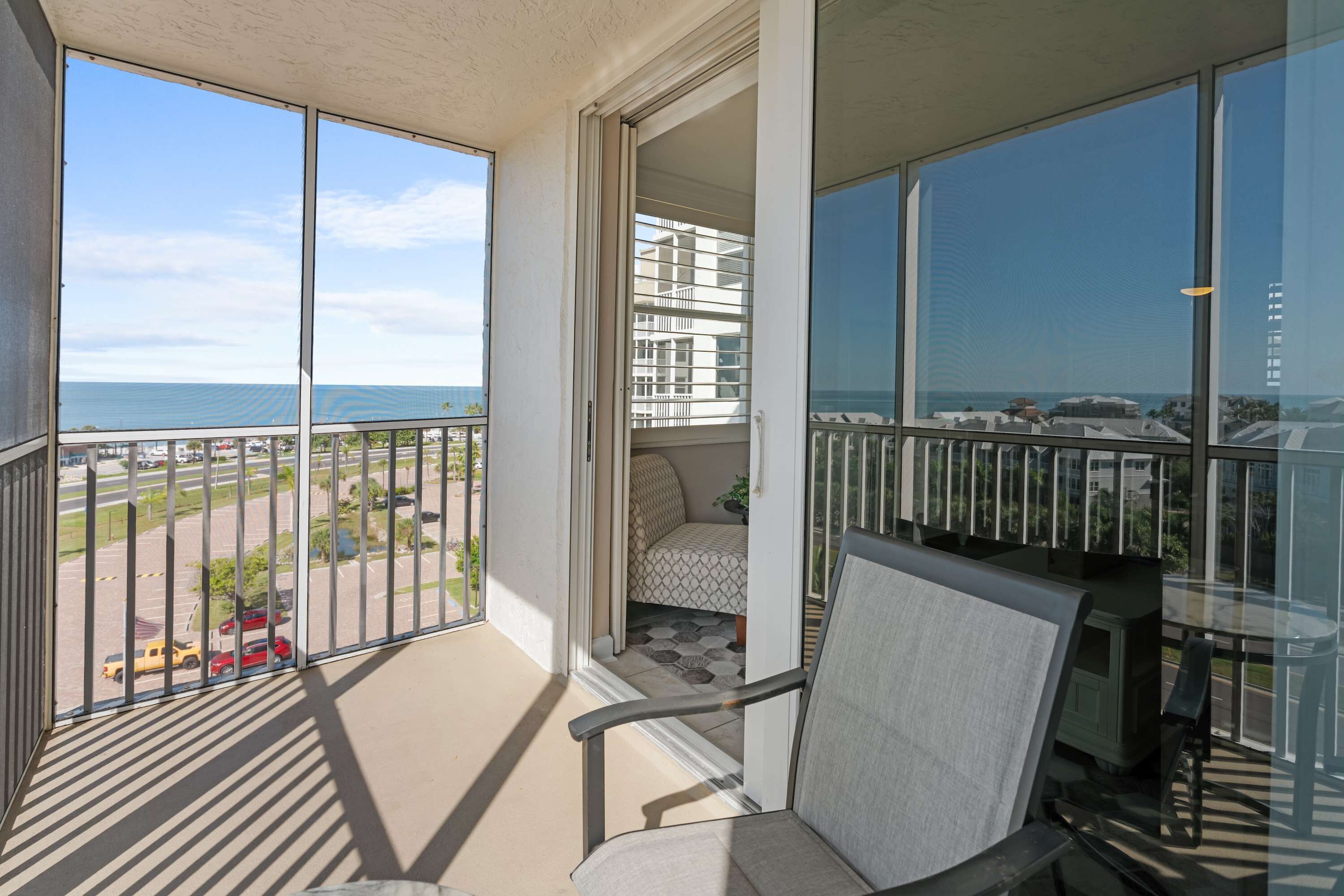 Een balkon met uitzicht op zee en een parkeerplaats.