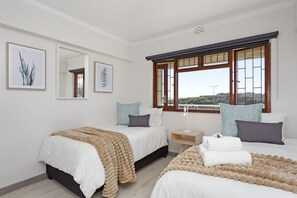 A bedroom with two beds, a large window, and artwork on the walls. - Cisterama 102 (Cape Town)