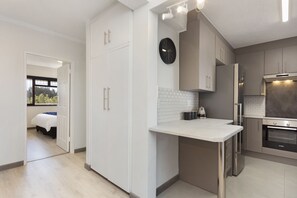 A modern kitchen with white cabinets, a built-in oven, and a countertop. - Cisterama 102 (Cape Town)