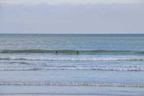 A beach with waves and two people surfing. - Cisterama 102 (Cape Town)