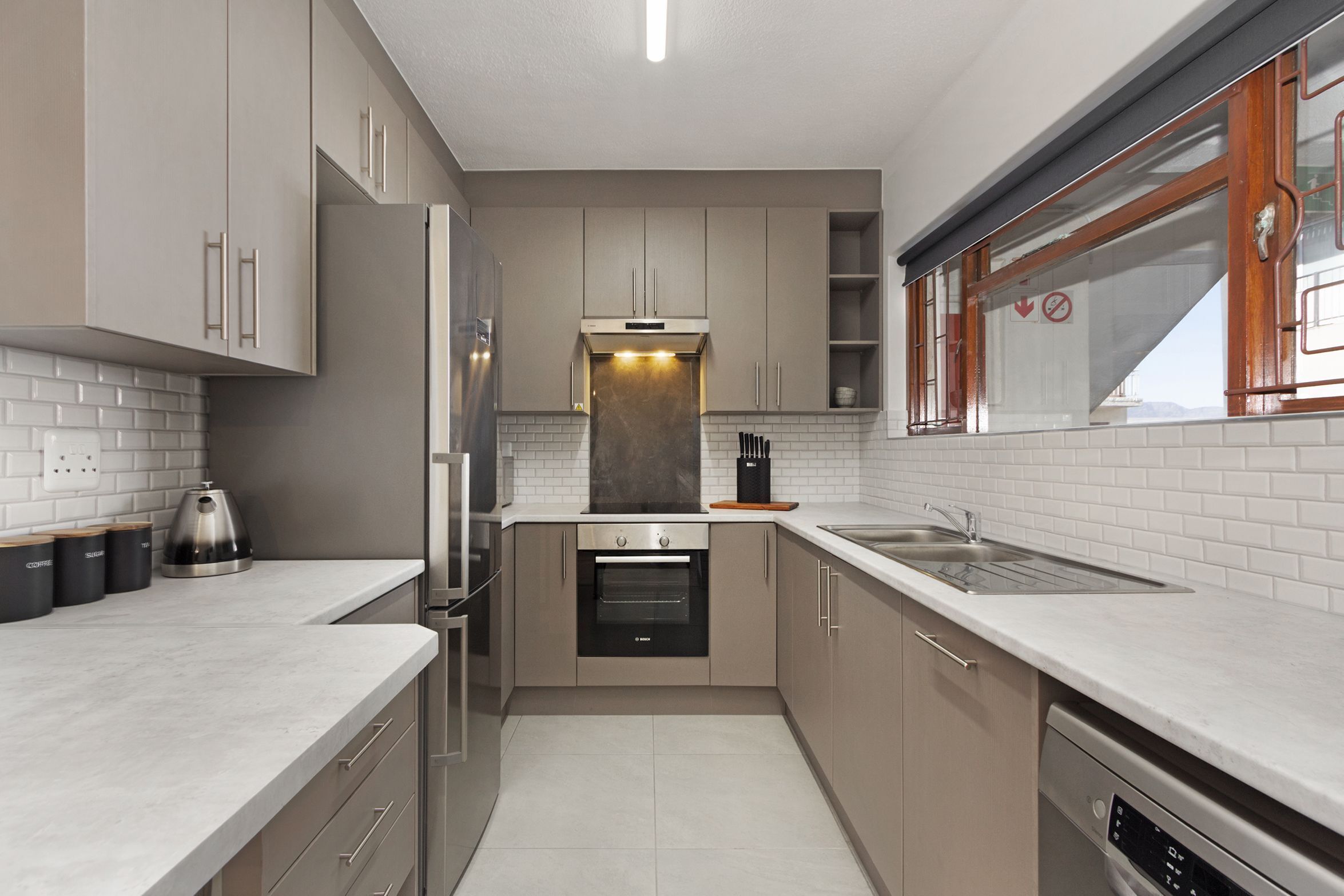 Una cocina moderna con horno empotrado, lavavajillas y refrigerador de acero inoxidable.