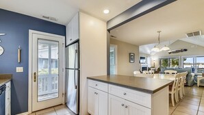 A modern kitchen with a large island, white cabinetry, and a stainless steel refrigerator.