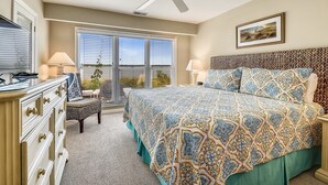 A bedroom with a bed, a dresser, a chair, a ceiling fan, and a window with blinds.