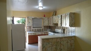 A kitchen with a refrigerator, stove, and cabinets.