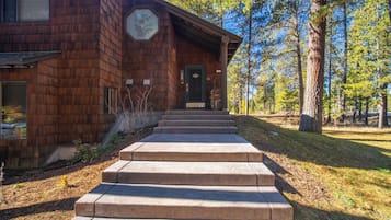 A wooden building with a green door, a large window, and a set of stone steps leading to the entrance.