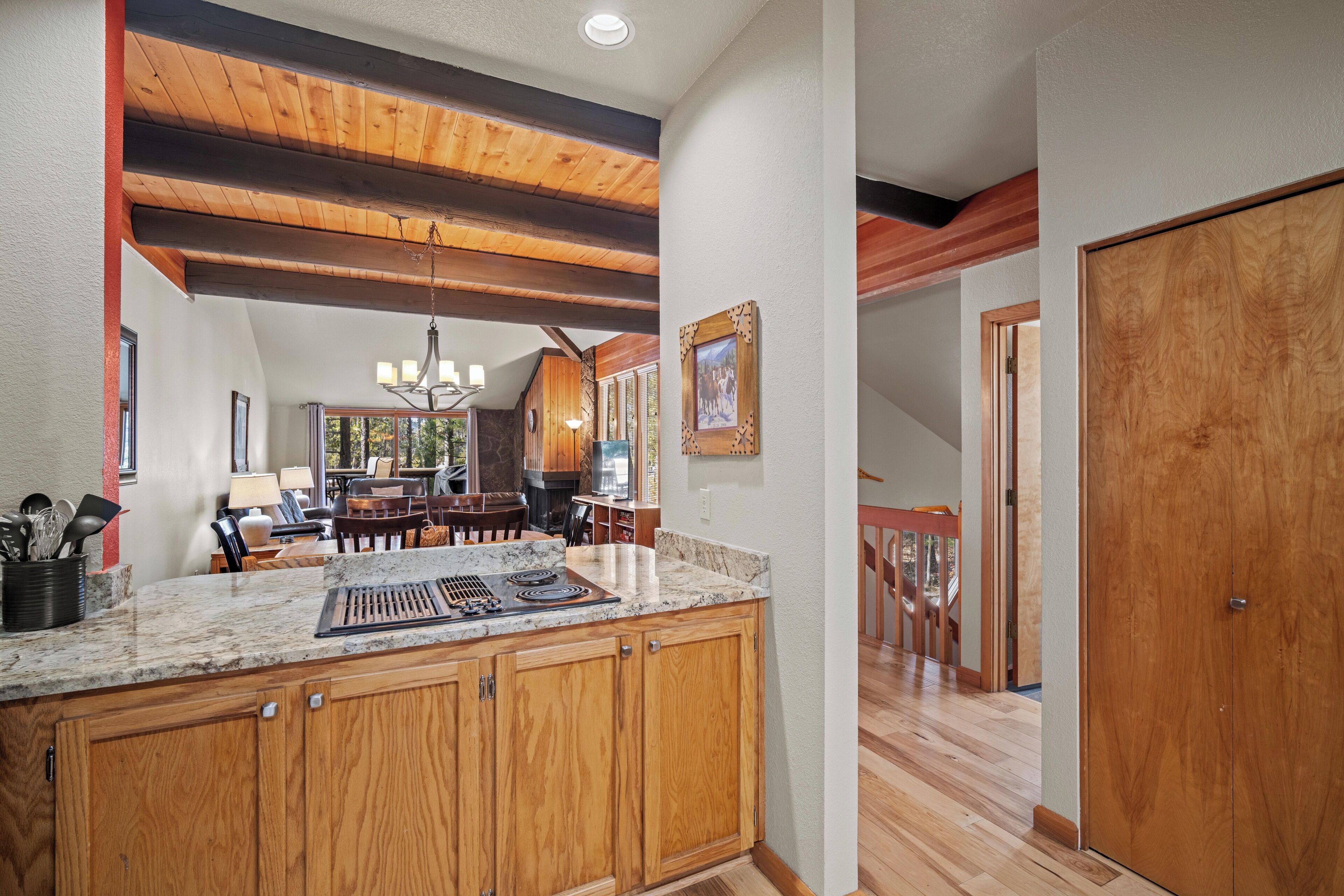 A kitchen with wooden cabinets, granite countertops, and a dining area with a chandelier.