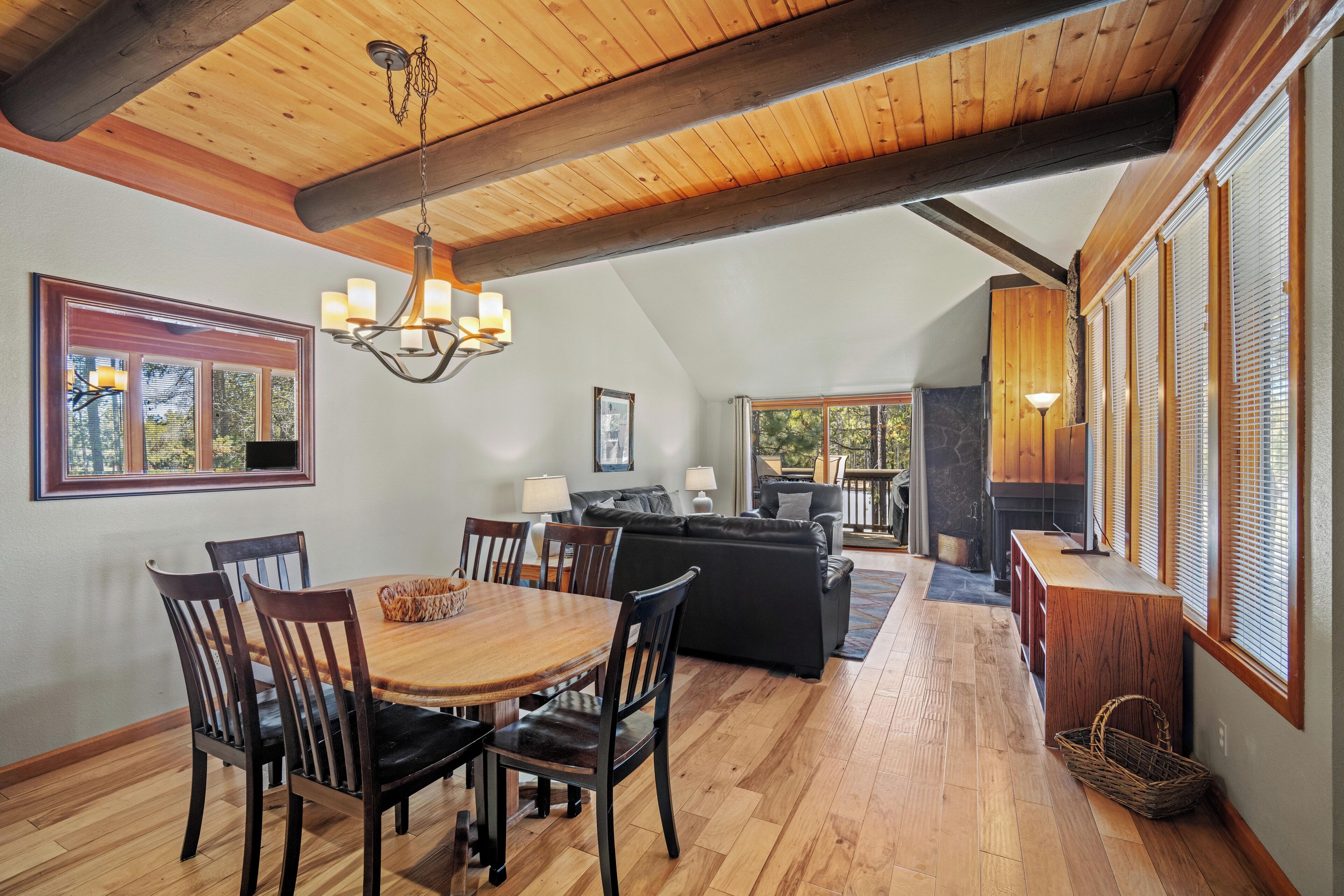 A spacious living area with a wooden ceiling, a dining table with chairs, a sofa, and a fireplace.