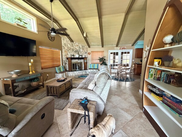 A living room with a sofa, a television, a fireplace, a dining area, and a bookshelf.