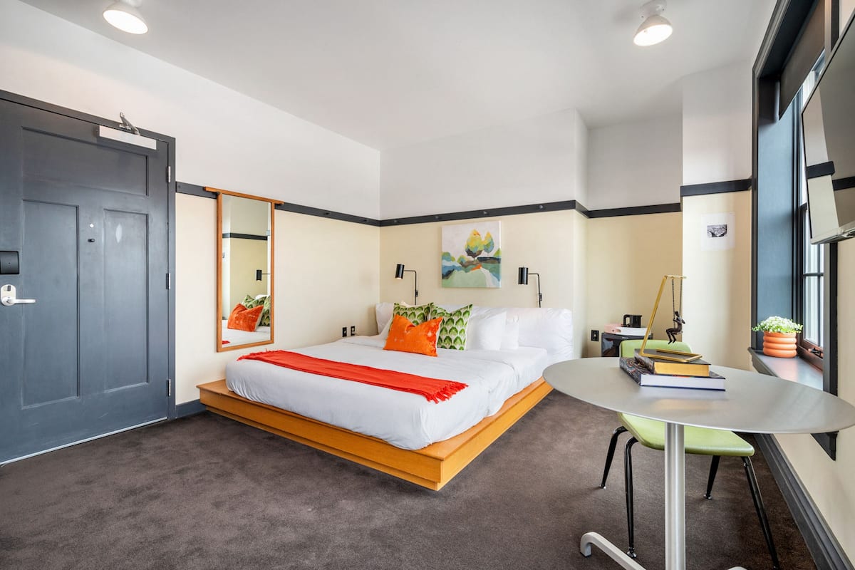 A modern hotel room with a bed, a round table, and a window.
