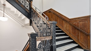 Una escalera de madera con barandillas de metal elaboradas y escalones de mármol.