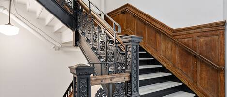 A wooden staircase with intricate metal railings and marble steps.