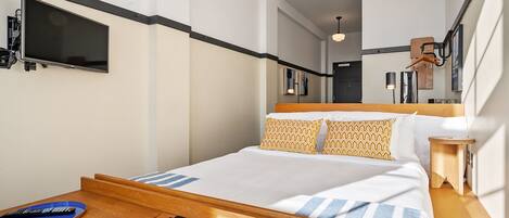 A modern hotel room with a bed, bedside table, and a mounted TV.