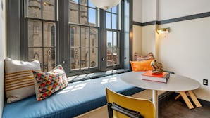 Una habitación con un ventanal grande, una mesa redonda y un banco acolchado azul.