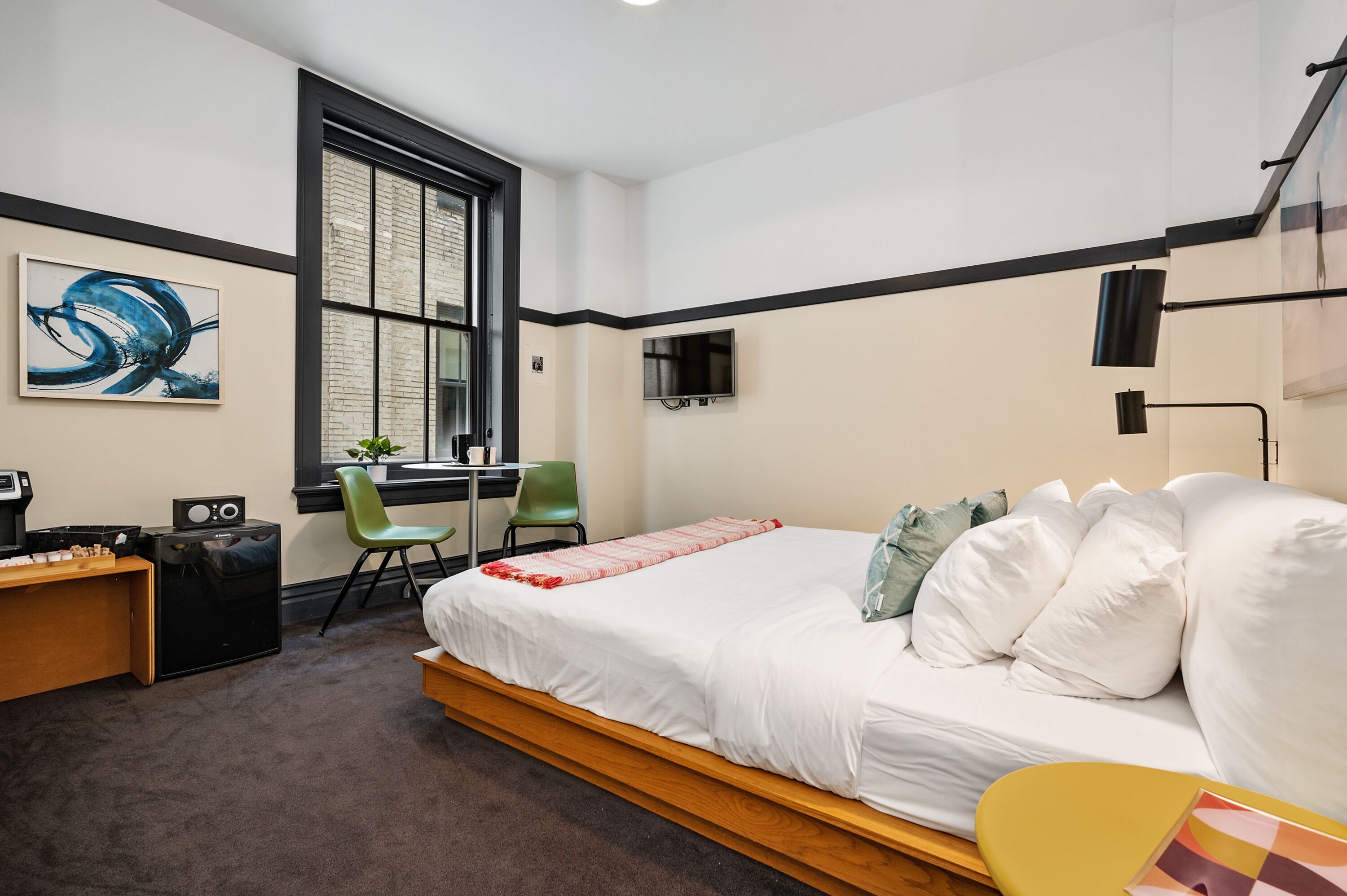 A modern bedroom with a bed, desk, chair, and a TV.