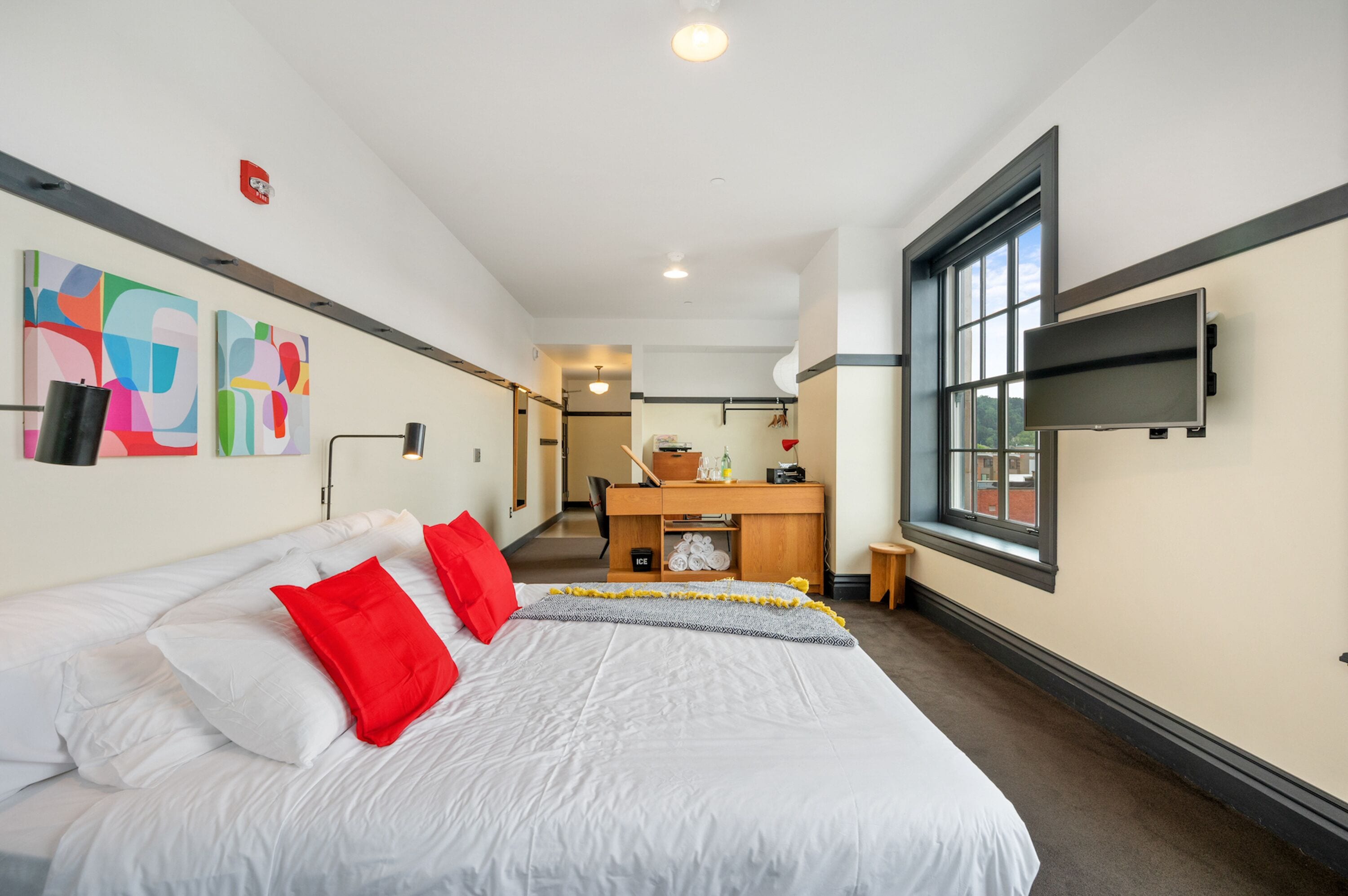 Habitación de hotel con una cama grande, un escritorio, un televisor y obras de arte en la pared.