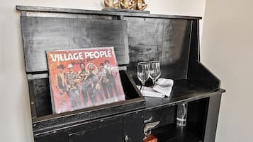 A black wooden cabinet with a vinyl record titled "Village People" and two wine glasses on top.